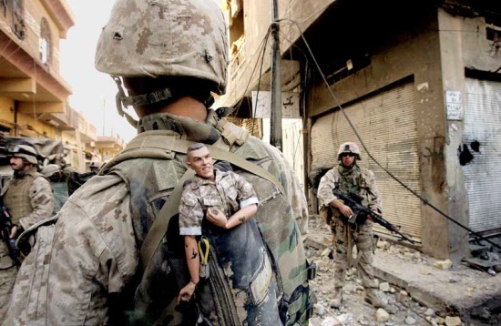 Anja Niedringhaus, A U.S. Marine of the 1st Division carries a GI Joe mascot as a good luck charm in his backpack as his unit pushes further into the western part of Fallujah, Iraq, November 14, 2004.